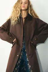 Trench color verde oscuro con cuello solapa combinado en pana marrón y manga larga. Detalle de acabados con trabillas y pinza en espalda. Bolsillos delanteros con solapa y botón a presión. Tejido encerado efecto lavado. Cierre frontal con botones a presión.