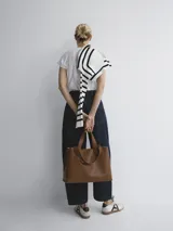 Bolso negro tipo tote bag con doble asa corta y correa larga extraíble.