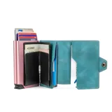 Billetera doble de cuero marrón con detalles en rosa. Cuenta con doble caja de aluminio con sistema de deslizamiento para tarjetas, clip para billetes y espacio adicional para documentos.