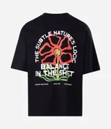 Remera de algodón negra, corte oversized, con estampa frontal de una flor estilizada en tonos rojo, amarillo y verde, y el texto "Balance ESTD. 1995" en blanco.