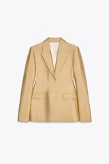 Blazer amplio color dorado confeccionado en hilatura con viscosa. Cuello solapa de muescas y manga larga. Bolsillos con solapa en delantero y de vivo en pecho. Forro interior. Cierre frontal con botones.