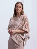 Vestido de fiesta color beige, de corte recto y largo a la rodilla, confeccionado en seda fría. Presenta una sobrecapa de microtul bordado con motivos florales.