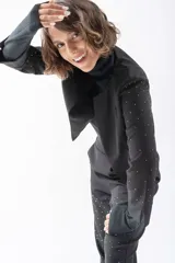 Chaqueta corta y abierta de color negro con detalles brillantes en los brazos, que añade un toque sofisticado al atuendo.