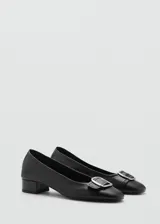 Zapato de cuero negro con tacón bloque y hebilla decorativa.