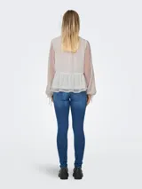 Blusa blanca con textura de lunares, cuello con volantes y lazo, cierre frontal con botones, mangas largas abullonadas con puños elásticos y corte peplum.