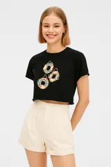 Remera cropped color rosa con estampado de conchas marinas en color rojo, corte holgado y cuello redondo.