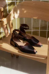 Sandalias bajas de cuero con estampado animal print de vaca en blanco y negro, con pulsera al tobillo y taco cuadrado.