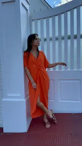 Vestido largo color naranja con escote en V y nudo frontal.