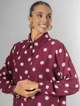 Camisa de manga larga en fibrana color bordó con estampado de lunares grandes en color crema. Presenta cuello camisero y cierre frontal de botones.