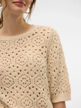 Suéter de punto calado color beige, con cuello redondo y mangas cortas. Corte estándar y tejido suave.