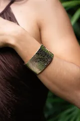 Brazalete ancho dorado con diseño de escamas.