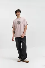 Remera de manga corta color rosa pálido con estampado circular en el frente.