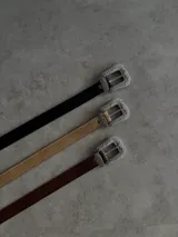 Cinturón de ecocuero negro con hebilla metálica plateada con diseño labrado.