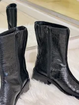 Bota negra de caña media con textura de cocodrilo, punta cuadrada y tacón bajo.
