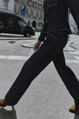 Jeans de mezclilla azul oscuro, tiro medio, corte recto y slim. Presenta costuras verticales marcadas en el frente de ambas piernas y viene con un cinturón de cuero marrón.