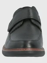 Zapato de cuero negro con ajuste de velcro, forro textil y plantilla de cuero y algodón orgánico. Suela de goma EVA con cortes para mayor flexibilidad.