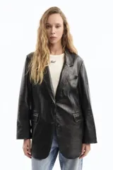 Blazer negro de cuero con solapas de muesca, cierre con un botón, bolsillos delanteros con solapa y corte holgado.