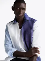 Camisa de manga larga con diseño color block en azul y blanco, confeccionada en algodón Oxford, con cuello abotonado, bolsillo de parche en el pecho, puños redondeados con botón y logo bordado en el bolsillo.
