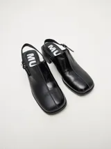Mocasines color beige con taco bloque de madera color negro y correa trasera ajustable.
