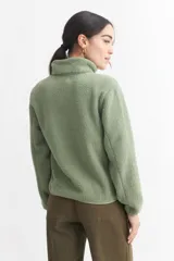 Campera negra de corderito con cierre frontal y cuello alto. Tiene un bolsillo con cierre en el pecho y bolsillos laterales.