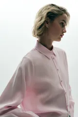 Camisa rosa de cuello solapa y manga larga. Tejido suave. Cierre frontal con botones a tono.