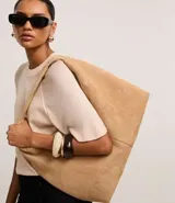 Bolso hobo grande color beige, confeccionado en gamuza sintética, con correa de hombro y cierre de cremallera.