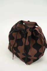 Bolso tipo bombonera tejido a crochet, con patrón geométrico en tonos rosa y marrón. Tiene cierre con cordón ajustable y correa de hombro.