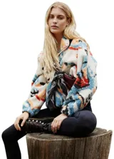 Campera de polar con estampado geométrico multicolor en tonos blanco, azul, naranja y negro. Presenta cuello alto, cierre frontal con botones a presión y un diseño holgado de hombros caídos.