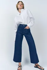 Pantalón de jean de tiro alto color negro con pierna ancha, bolsillos delanteros y traseros, y cierre frontal con cremallera y botón metálico.