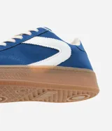 Championes deportivos de mujer modelo chuteira, color azul con aplique lateral en forma de 'V' blanca. Presenta capellada de gamuza sintética, cordones blancos y suela gruesa de goma color caramelo.