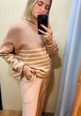 Sweater de punto color rosa con rayas horizontales color crema, cuello alto y cierre en la espalda.