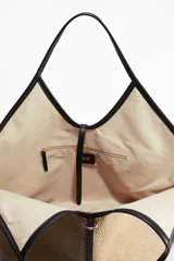 Bolso shopper de paja de plástico trenzada color beige con detalles en tejido revestido negro. Asas estrechas, correa fina en la parte superior y bolsillo interior con cierre.