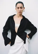 Camisa blanca de lino, de corte oversize, manga larga con puños abotonados, cuello camisero y cierre frontal con botones.