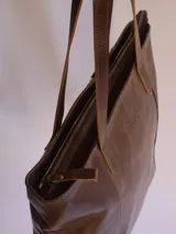 Bolso tote de cuero color marrón con cierre superior y doble asa de hombro. Incluye bolsillo interior y llavero.