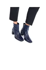 Botines de cuero vacuno azul marino con efecto croco brillante. Tienen caña media, cierre lateral y tacón bloque negro brillante de aproximadamente 7 cm.