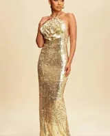 Vestido largo de fiesta color dorado con lentejuelas y cuello halter con detalle de flor grande en el escote.