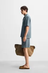 Bermuda azul de tejido con mezcla de algodón, corte relaxed fit, cintura elástica ajustable con cordón, bolsillos delanteros y detalle de bolsillo trasero de vivo.