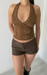 Top tipo corset marrón de gamuza sintética, con cuello halter y cordones cruzados en el frente.
