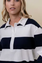 Sweater de manga larga con diseño de rayas anchas horizontales en azul marino y blanco. Posee cuello polo con cartera de botones y calce relajado.