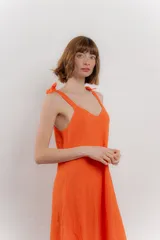 Vestido corto amarillo de lino, con escote en V y tirantes finos con detalle de moño en los hombros.