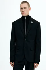 Blazer negro de corte slim fit, con solapas de muesca finas y ojal decorativo. Modelo de botonadura sencilla con bolsillo superior insertado, bolsillos delanteros con solapa, dos bolsillos en el interior y botones decorativos en los puños. Abertura doble atrás.
