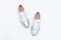 Zapatillas Magnolia plateadas con detalles en blanco y suela marrón.