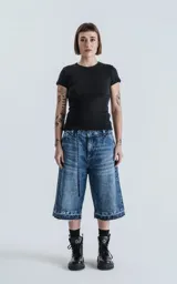 Bermuda larga de denim con calce oversize, desgaste y ruedo desflecado.