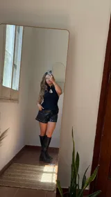 Top negro de gabardina elastizada, con cuello halter y abertura en el pecho. Se ajusta con tiras en la espalda y tiene tiras decorativas en el frente.