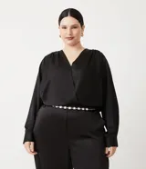 Blusa de satén negra con escote cruzado, manga larga y elástico en la cintura.