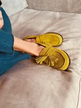 Alpargatas tipo mocasín de gamuza color amarillo mostaza, con detalle de flecos en la capellada.