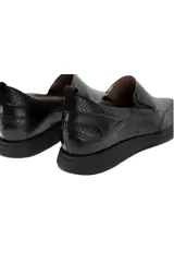 Zapato slip-on negro de cuero vacuno con textura delicada y acabado en color nácar. Tiene inserciones elásticas laterales y suela flexible con tecnología Antistress.