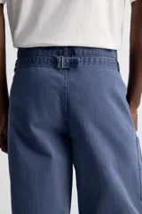Pantalón azul de corte recto, con cintura ajustable, bolsillos laterales y traseros, y bolsillo tipo plastrón en la pierna. Tiene un lavado vintage con efecto de manchas.