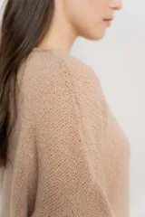 Sweater beige de tejido bouclé, con cuello redondo y mangas largas.