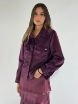 Chaqueta color beige con cuello camisero, cierre frontal con botones, bolsillos de parche con solapa y manga larga.